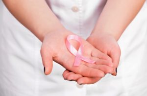 A woman holding her hands with a pink ribbon.