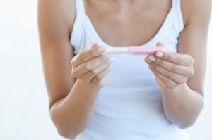 A woman holding a pink baby 's first toothbrush.